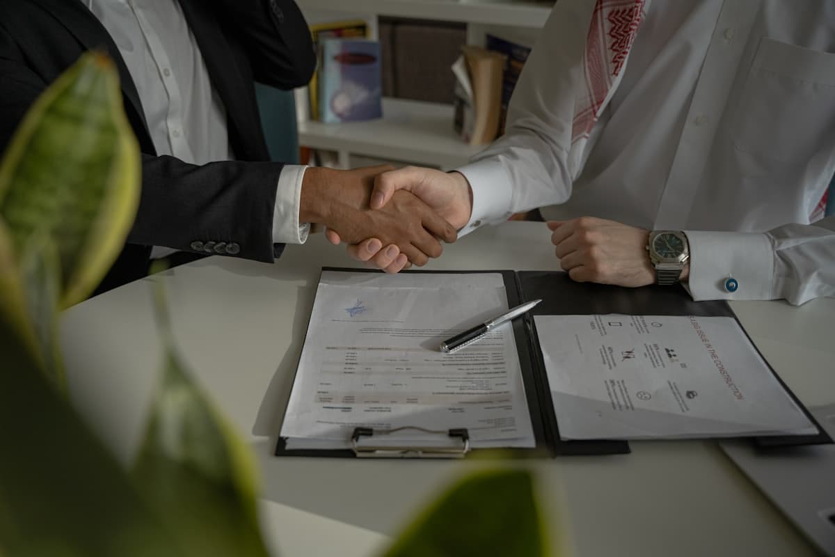 A handshake across a desk over completed paperwork