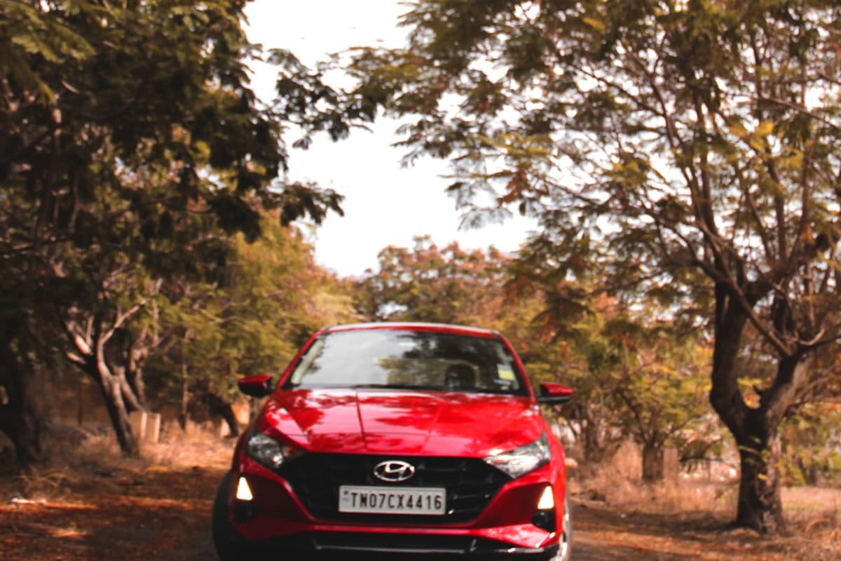 A new red hatchback on a tree-lined road